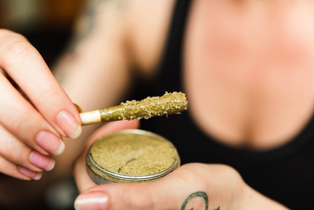 mulher segurando baseado com kief polvilhado em cima